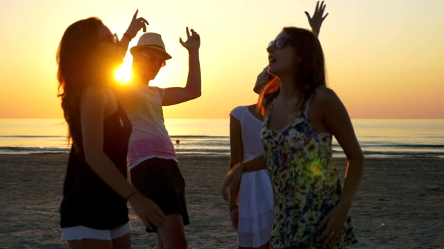 Vier-Freunde-tanzen-am-Strand-in-der-Abenddämmerung