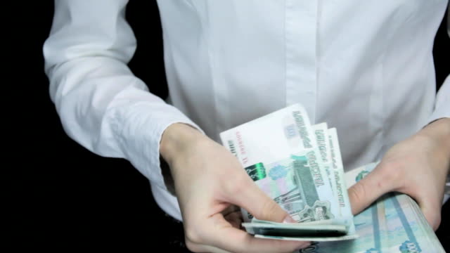 Woman-hesitantly-counts-the-money-and-stacks-of-bills-into-one-image,-Russian-rubles