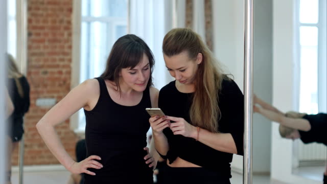Niedliche-glücklich-Pole-Tänzer-eine-Pause-von-ihrem-Training-und-social-Networking-mit-einem-Handy