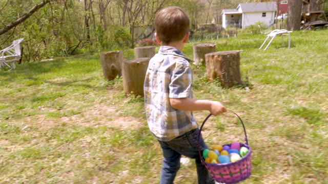 Joven,-concentrándose-en-encontrar-huevos-de-Pascua-al-caminar-en-un-patio
