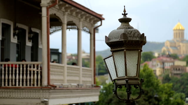 Luz-de-calle-antigua-cerca-de-edificio-antiguo-con-terraza-al-aire-libre,-día-de-lluvia-en-Tbilisi