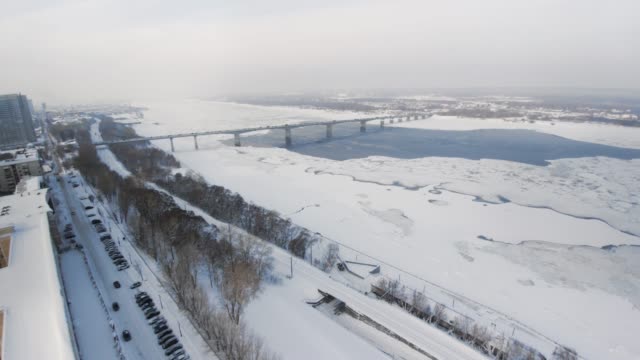 Snowy-winter-in-beautiful-city-or-town.-Clip.-Top-view-of-frozen-river,-many-cars-on-road,-ancient-buildings.-Charming-winter-period-in-big-city.-Wonderful-panorama