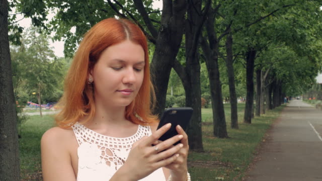 ginger-student-using-smart-phone-outdoor.