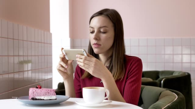 Young-beautiful-brunette-girl-doing-photo-of-cake-while-sitting-in-cafe.-Problem-today,-social-network.-60-fps