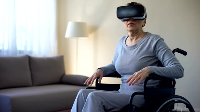 Aged-female-sitting-in-wheelchair-and-wearing-virtual-reality-headset,-game