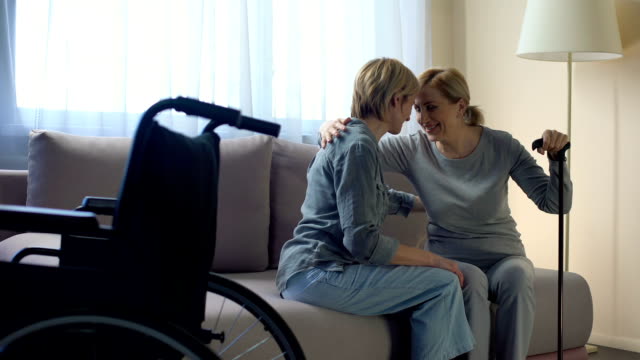 Behinderte-Mutter-auf-der-Couch-sitzen-und-im-Gespräch-mit-Tochter,-familiäre-Unterstützung
