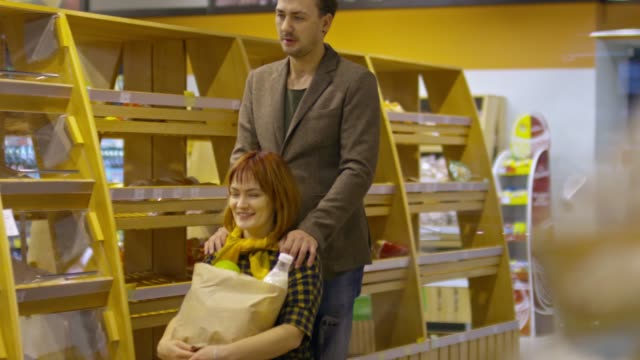 Amoroso-esposo-empujando-en-silla-de-ruedas-mientras-compras-en-supermercado