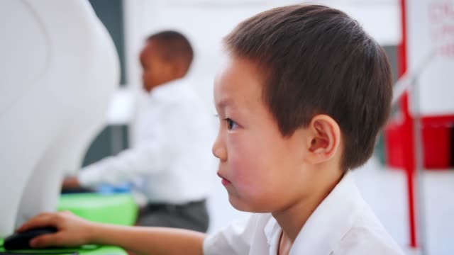 Asian-schoolboy-using-computer-at-a-science-centre,-close-up