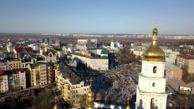 A-bird's-eye-view,-panoramic-video-from-the-drone-in-FullHD-to-the-Saint-Sophia's-Cathedral,-Sofiyivska-Square,-left-bank-of-city-in-the-city-of-Kiev,-Ukraine.-People-on-the-square-on-Easter-days.