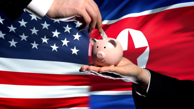 Inversión-estadounidense-en-Corea-del-norte,-poniendo-dinero-en-piggybank-fondo-bandera-de-mano
