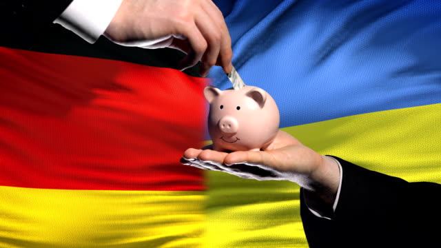 Germany-investment-in-Ukraine-hand-putting-money-in-piggybank-on-flag-background