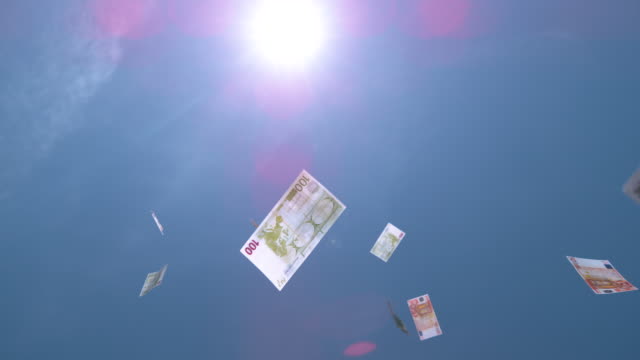 SLOW-MOTION-CLOSE-UP:-Dollar-und-Euro-Rechnungen-fallen-aus-dem-sonnigen-blauen-Himmel