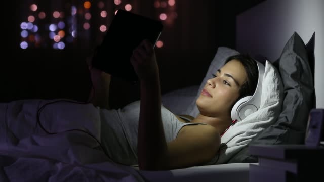 Glückliches-Mädchen-ansehen-von-Videos-in-einer-Tablette-in-der-Nacht