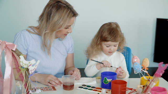 Mother-and-her-little-daughter-painting-Easter-eggs