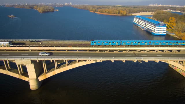 Antenne,-Top-Aussicht-von-Drone:-Metro-Zug-fährt-über-eine-Brücke-mit-PKW-und-LKW.