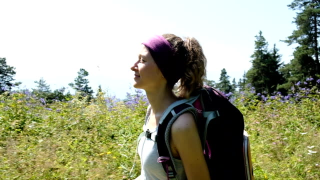 Glückliche-Frau-Tourist-an-einer-Wanderung-geht-mit-einem-Rucksack-und-lächelt,-Zeitlupe,-Kamerabewegung