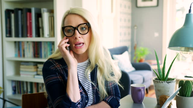 Attraktive-blonde-Geschäftsfrau-Büro-am-Smartphone-zu-Hause-sprechen
