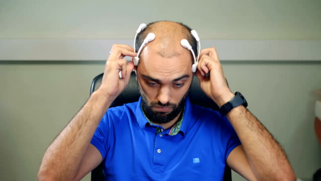 Un-hombre-con-ondas-cerebrales-exploración-auricular-trabajando-con-la-computadora.