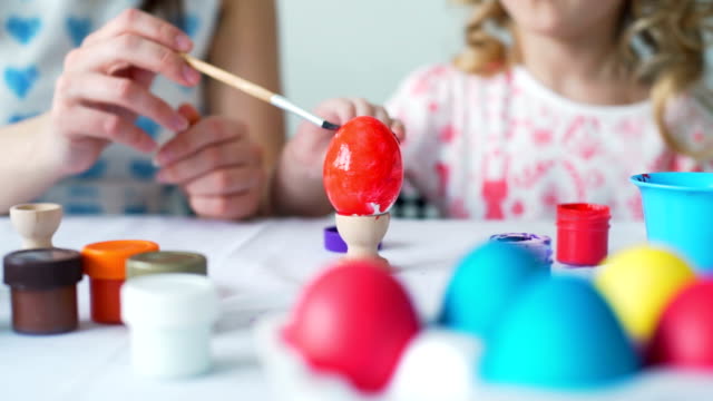 Pequeña-niña-y-su-madre-pintando-huevos-para-Pascua