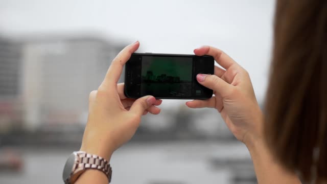 Mit-Smartphone-die-Hände-asiatischer-Frau-schließen-Senden-von-Foto-Social-Media-neben-Zaun-am-Fluss