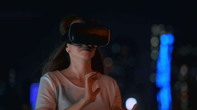 Young-woman-in-virtual-reality-glasses-in-the-night-city-moves-her-hands