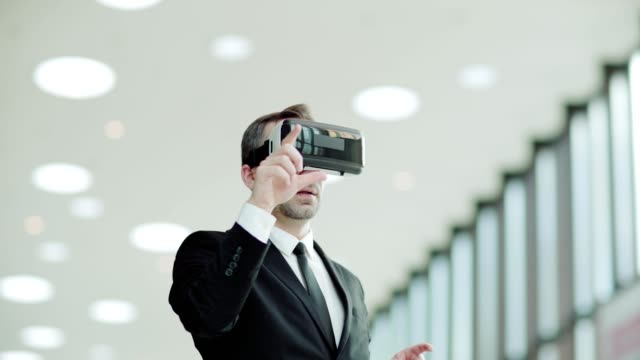 Panning-medium-shot-of-middle-aged-businessman-in-suit-wearing-virtual-reality-headset-and-browsing-data