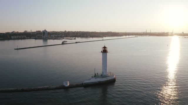 Aerial-shot-of-white-lighthouse-near-sea-port,-360-view
