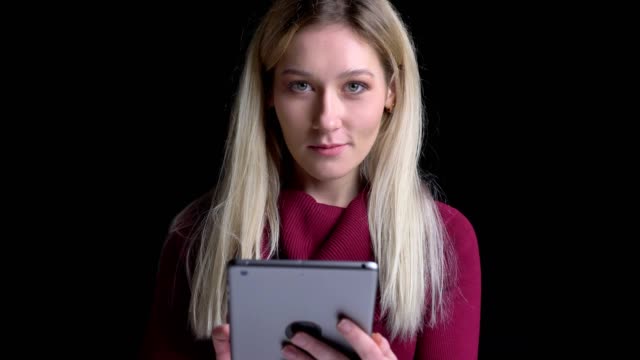 Nahaufnahme-von-jungen-hübschen-kaukasischen-Frau-mit-dem-Tablet-dann-Blick-auf-Kamera-mit-Hintergrund-isoliert-auf-schwarz