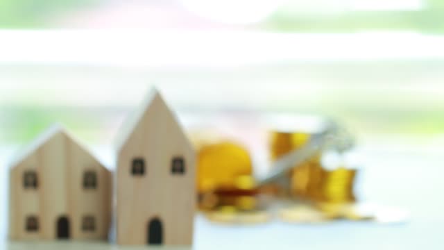 Finanzierung-Business-Immobilien-Anlagekonzept,-Holz-Haus-Modell-mit-Geld-Goldmünzen-auf-dem-Schreibtisch-im-Büro-Hintergrund-mit-Geschäftsmann-halten-Hände.-Sparen-oder-Darlehen,-Hypothek-neues-Haus-für-Familie