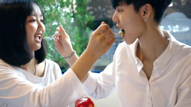 Joven-asiática-lesbiana-pareja-alimentando-dulce-arco-iris-pastel,-MOMENTO-LGBT-Amor-Slow-motion