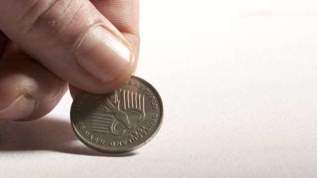 Hand-putting-2-Deutsche-Mark-coin-on-desk.-Obverse-side-showing-eagle