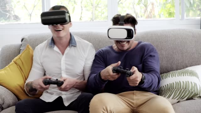 Gay-couple-relaxing-on-couch-playing-virtual-reality-games.-Exciting-mood.-Masks-off.