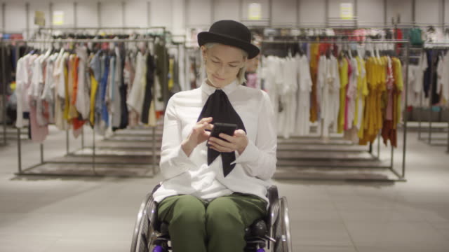 Behinderte-Frau-mit-Telefon-im-Kleiderladen