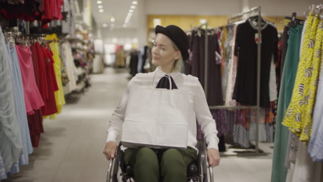 Frau-im-Rollstuhl-Einkaufen-in-Kleiderladen