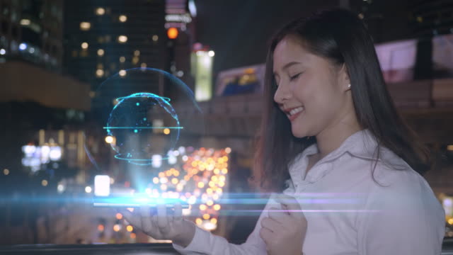 Joven-mujer-asiática-sonriente-negocios-usando-teléfono-inteligente-interactuar-un-holograma-big-data-3D-Earth,-red-avanzada-tecnología-del-futuro-en-la-pantalla-del-teléfono-inteligente.-ciudad-de-fondo-Bangkok-Tailandia.