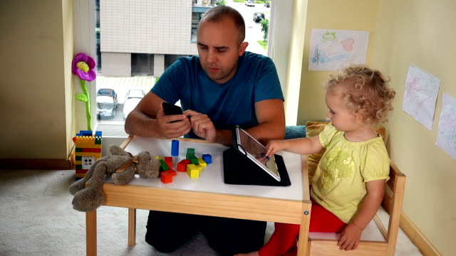 Vater-mit-Smartphone-und-Tochter-Mädchen-mit-Tablet-Computer