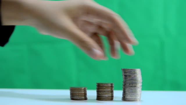 Nahaufnahme-Schuss-Hand-der-Frau-entfernen-Stapel-der-Münzen-über-grünen-Hintergrund