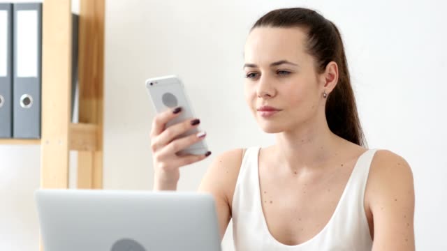 Frau-mit-Smartphone-Anwendungen-am-Arbeitsplatz-im-Büro