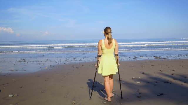 CLOSE-UP:-Strong-independent-woman-with-crutches-on-summer-holidays-at-the-beach