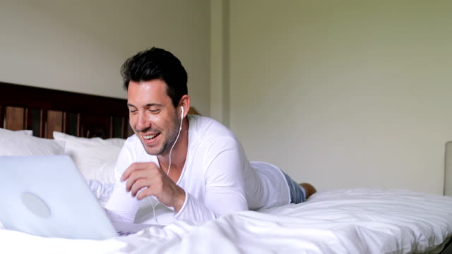 Junger-Mann-mit-Laptop-Computer-Video-Chat-Gespräch-Kerl-reden-auf-Bett-Schlafzimmer-morgens-liegend