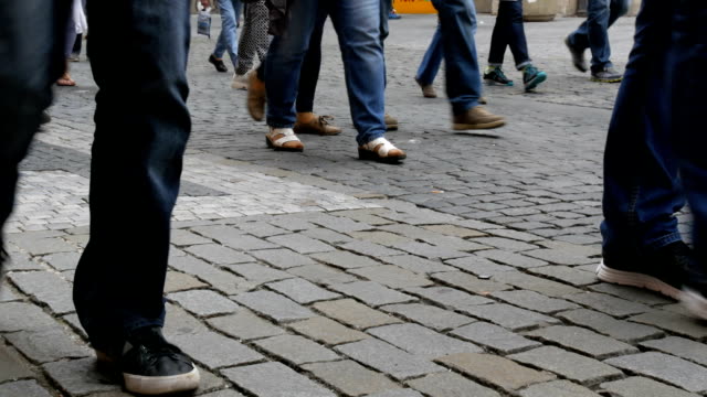 Muchos-pies-una-muchedumbre-de-personas-paseando-por-los-adoquines-de-la-ciudad
