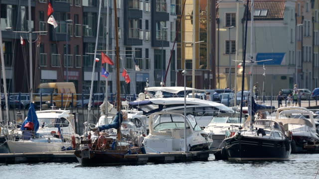 Hermoso-blanco-yates-con-agitando-banderas-estacionado-en-el-puerto-de-Gdansk,-transporte-de-agua