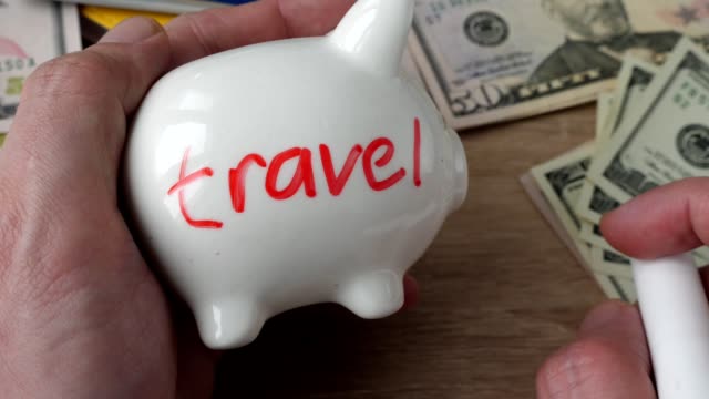 Savings-and-money-for-holidays-and-vacation.-Man-draws-a-word-travel-on-a-piggy-bank.