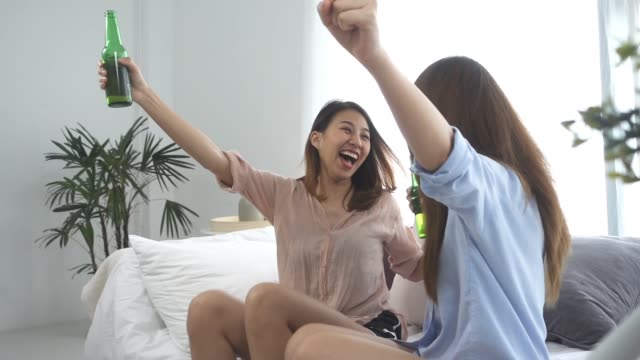 Slow-motion---Group-of-friends-asian-women-fanatic-football-fans-watching-soccer-game-on-television-celebrating-goal-on-couch-screaming-excited-and-ecstatic-in-crazy-happy-face-expression-with-beer.