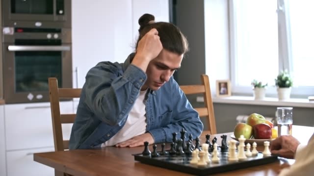 Hombre-mayor-en-silla-de-ruedas-jugando-al-ajedrez-con-su-nieto