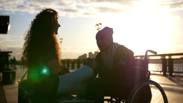 Junge-Behinderte-jungen-Mann-im-Rollstuhl-mit-junge-Frau,-die-zusammen-den-Sonnenuntergang-genießen