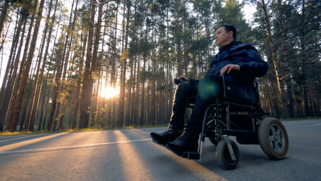 Physically-challenged-man-is-moving-in-a-powered-wheelchair-along-the-road