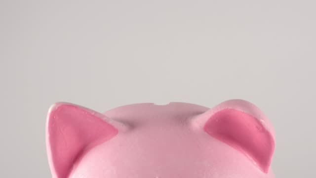 Zeitraffer:-Nahaufnahme-von-männlichen-Hand-wirft-Münzen-in-ein-rosa-Schweinchen-sparschweinchen