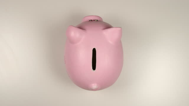 TOP-VIEW:-Human-hand-throws-a-coin-into-pink-pig-money-box