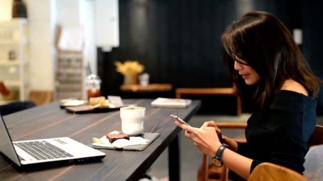 Mujer-asiática-disfrutando-de-su-café-y-smartphone-en-café